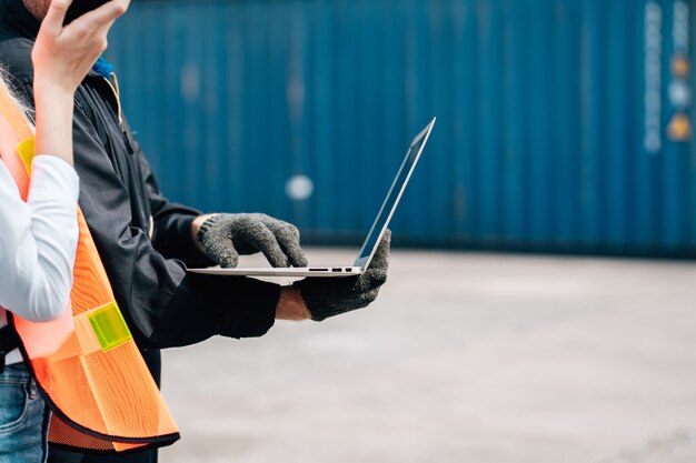 workers-teamwork-man-woman-safety-jumpsuit-workwear-with-yellow-hardhat-use-laptop-check-container-cargo-shipping-warehouse_42493-361